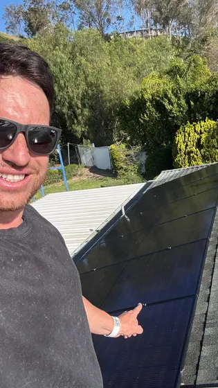 Person beside rooftop solar panels