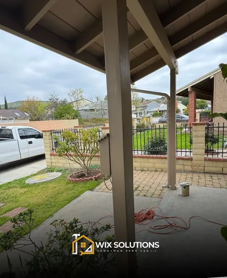 A white truck is parked under a covered porch.