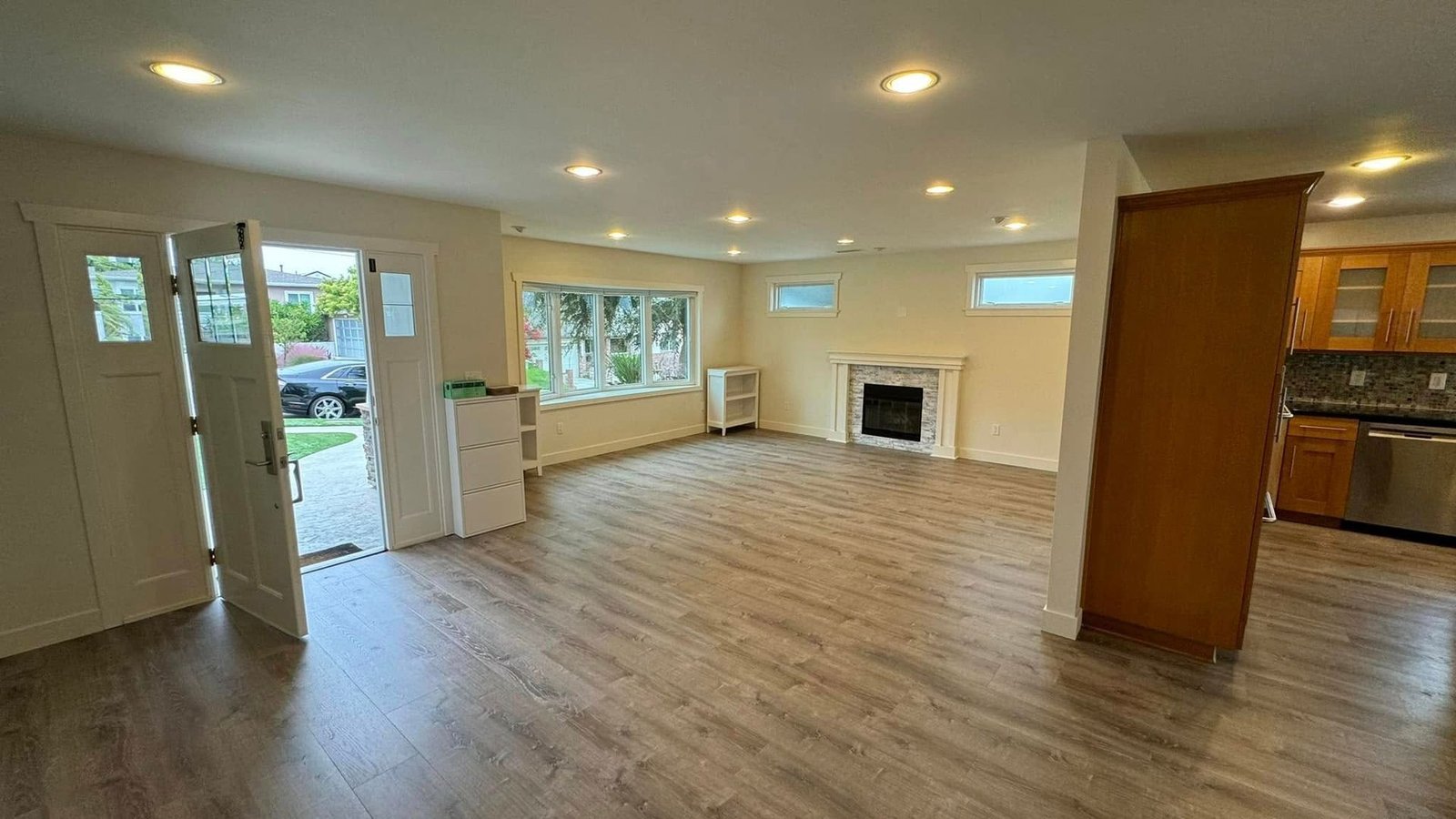 A large empty living room with hardwood floors and a fireplace.